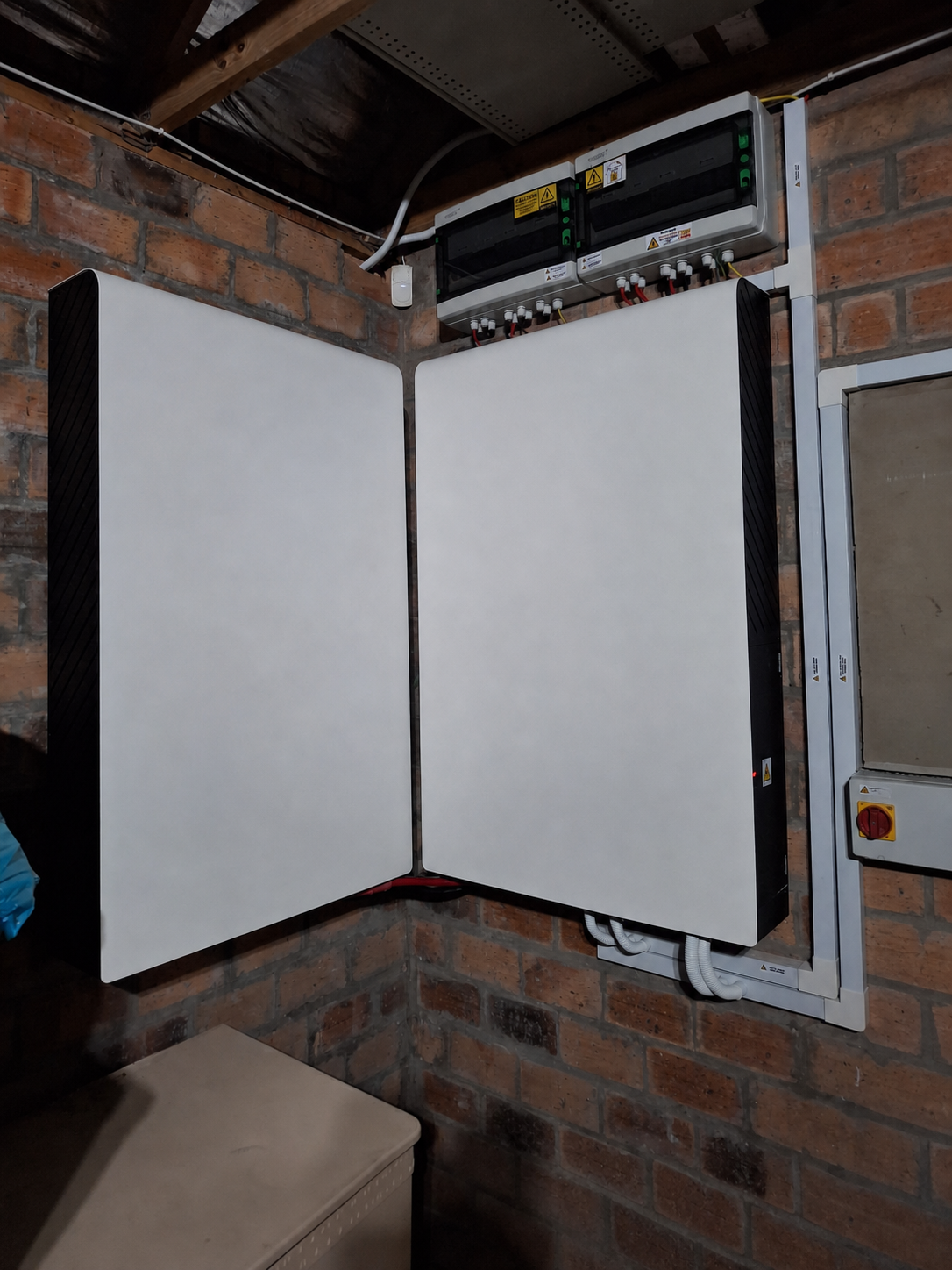 Two indoor solar inverter and battery cabinets mounted on a brick wall